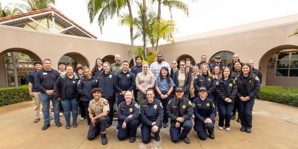 A group of adults participating in the Humane Law Academy pose in a courtyard at San Diego Humane Society.
