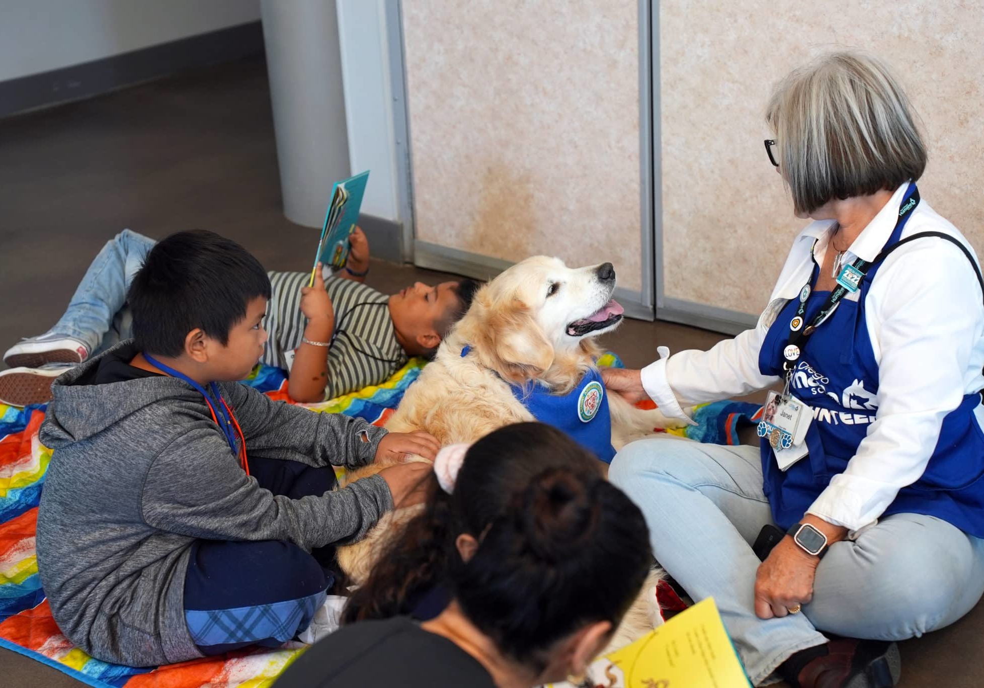 A group of children gathered around a dog with an adult